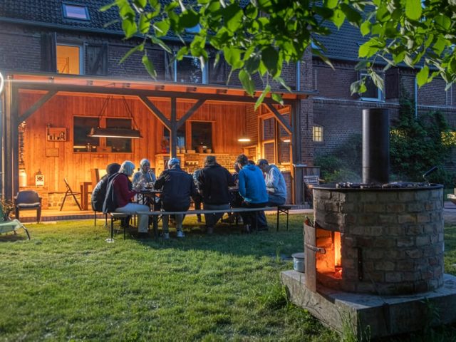 Gruppe an Feuerstelle und Außenküche der Alten Brennerei